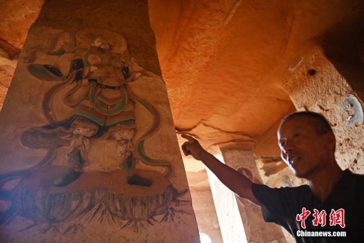 7月15日，甘肅省平涼市涇川縣百里石窟長廊羅漢洞石窟內，該窟文保員郭建平介紹窟內石刻彩繪壁畫。郭建平家中三代人曾自發(fā)保護羅漢洞石窟。羅漢洞石窟遺存40余個窟龕，以北魏至清代風格為主。中新社記者 李亞龍 攝</p>
<p>