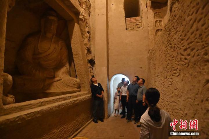 7月15日，游人參觀甘肅省平涼市涇川縣百里石窟長廊中的王母宮石窟。百里石窟長廊位于涇川縣境內，由512個石窟、5眼窟中石井組成，現(xiàn)存王母宮石窟、鳳凰山石窟、南石窟寺、丈八寺石窟、羅漢洞石窟、太山寺石窟等規(guī)模較大的石窟群，還有數量眾多的小石窟群。王母宮石窟又名千佛洞，該窟設計宏大，造像生動，窟內擁有造像數百尊，是較為珍貴的佛教文化歷史遺存。中新社記者 李亞龍 攝</p>
<p>
